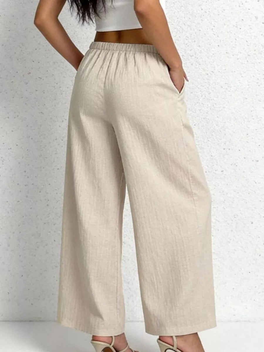 Relaxed beige cotton wide-leg pants with adjustable drawstring waist and pockets.