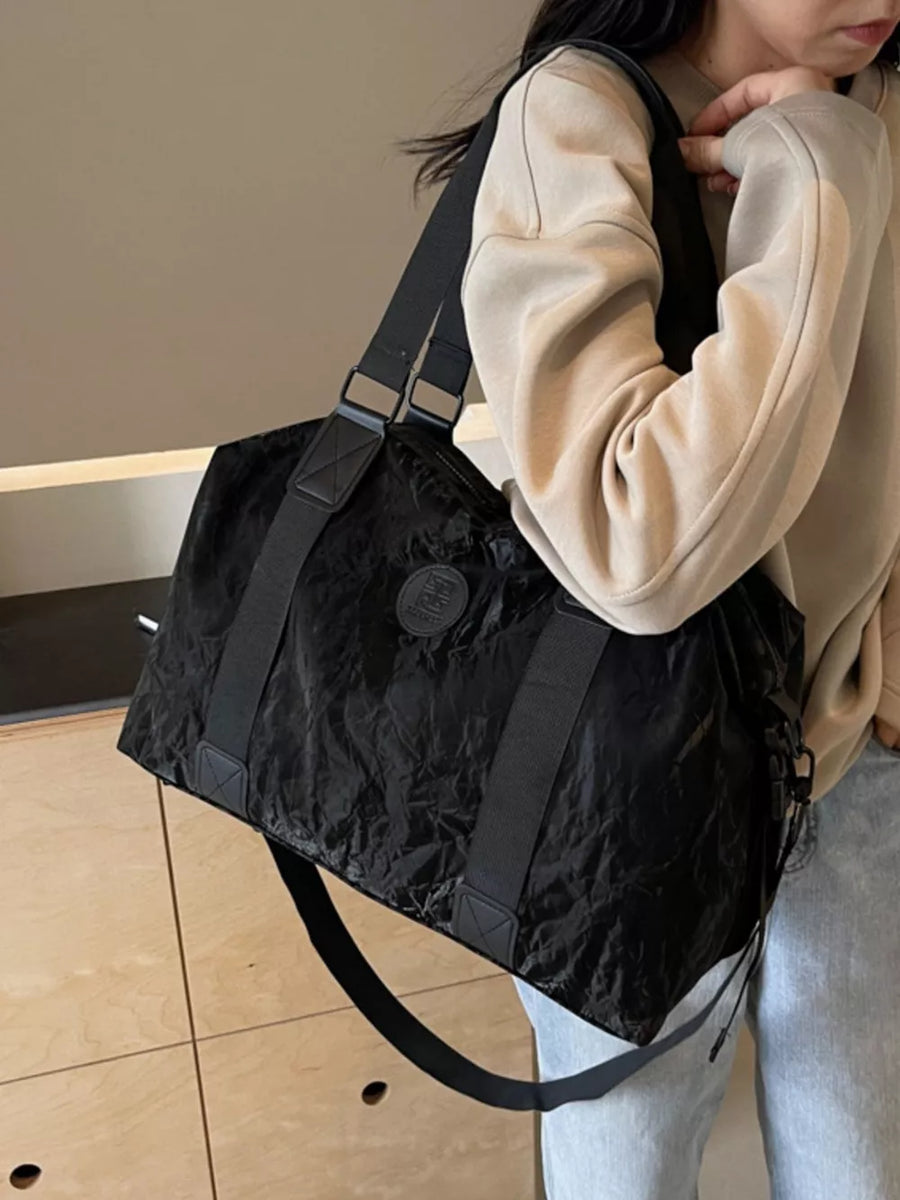 Chic black oxford cloth travel bag with adjustable strap and logo detail.