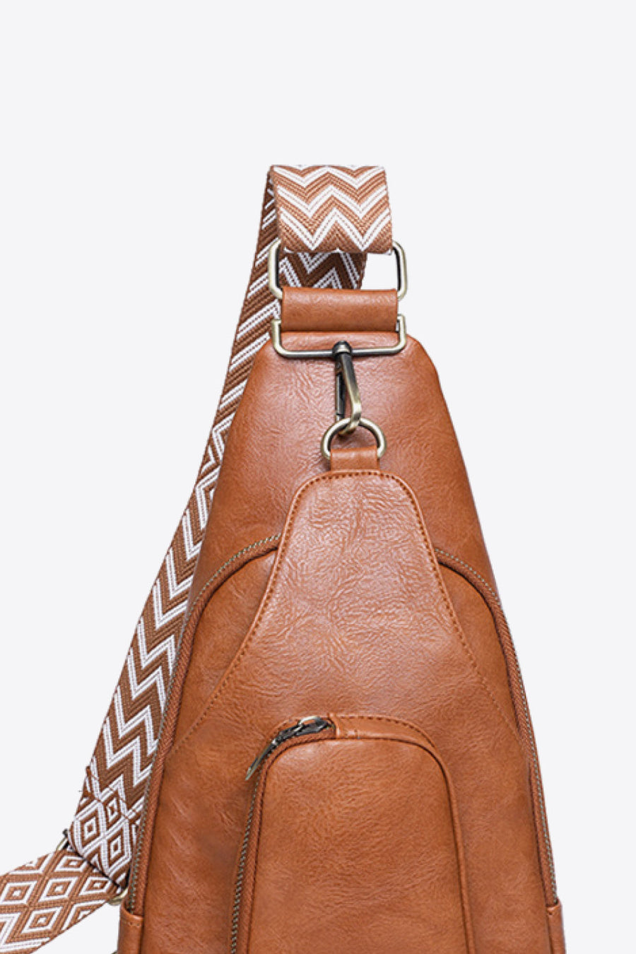 Honey PU sling bag with chevron strap detail and front zip pocket.