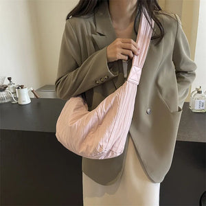 Pink quilted crescent shoulder bag with a ruched effect and wide strap.