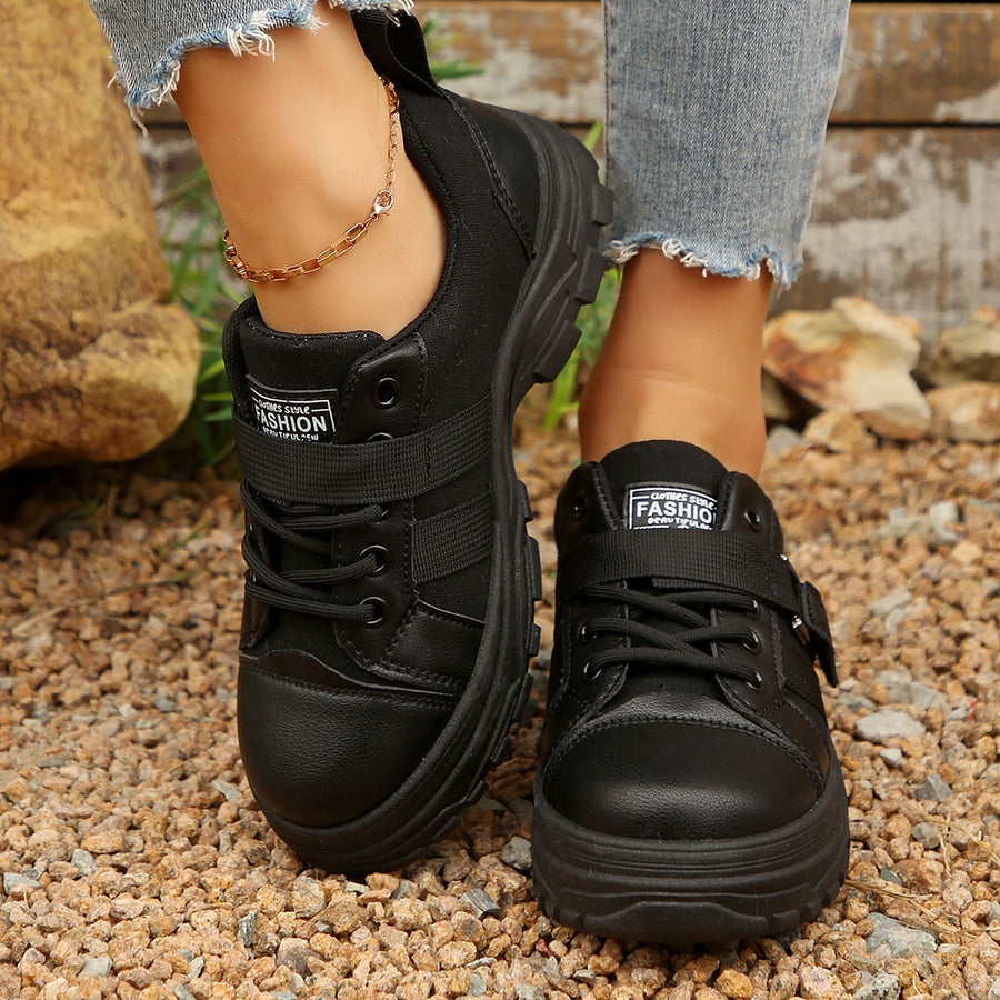 Black lace up platform sneakers with buckle strap detail and chunky sole.