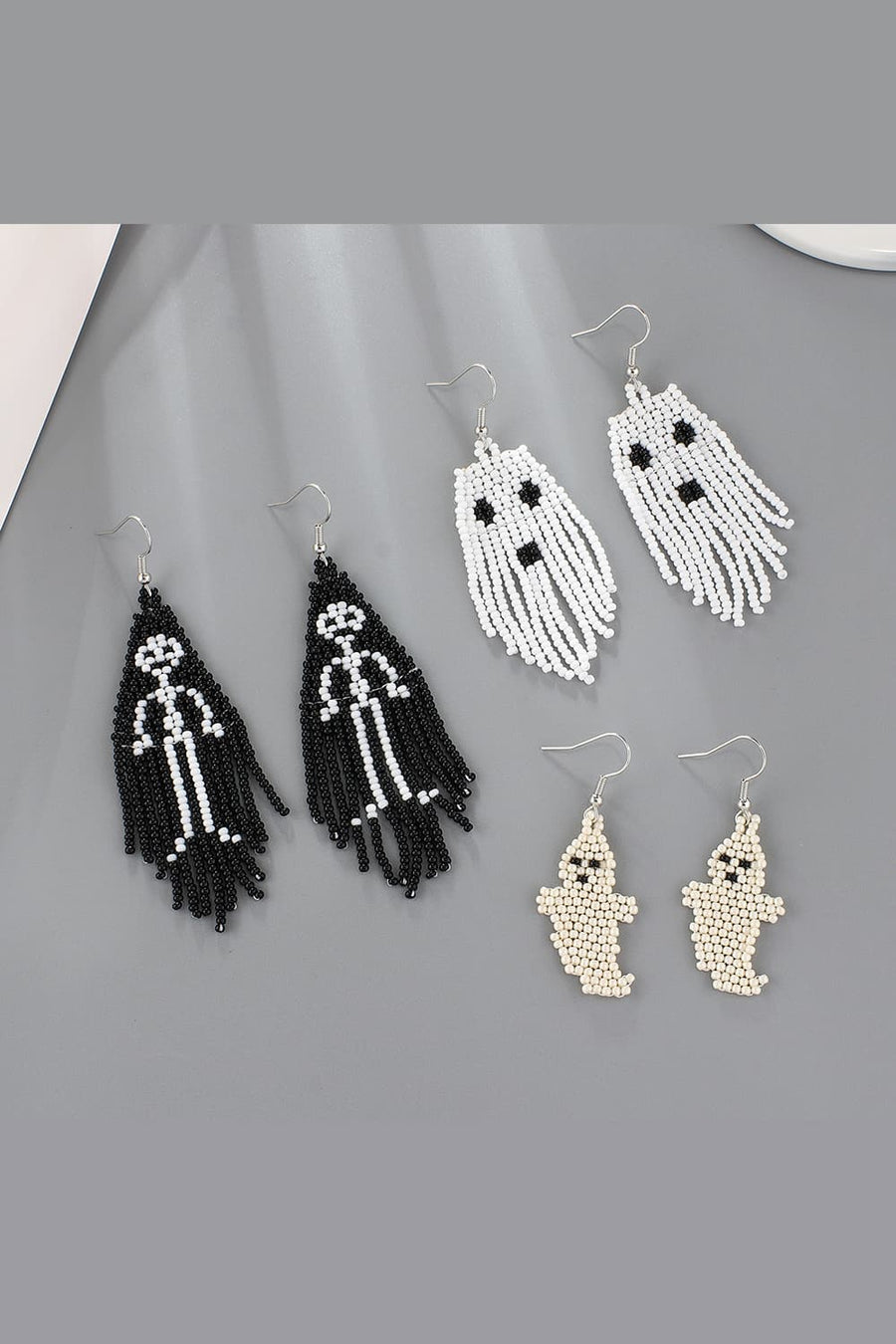 Beaded ghost and skeleton fringe earrings in ivory, black, and white.