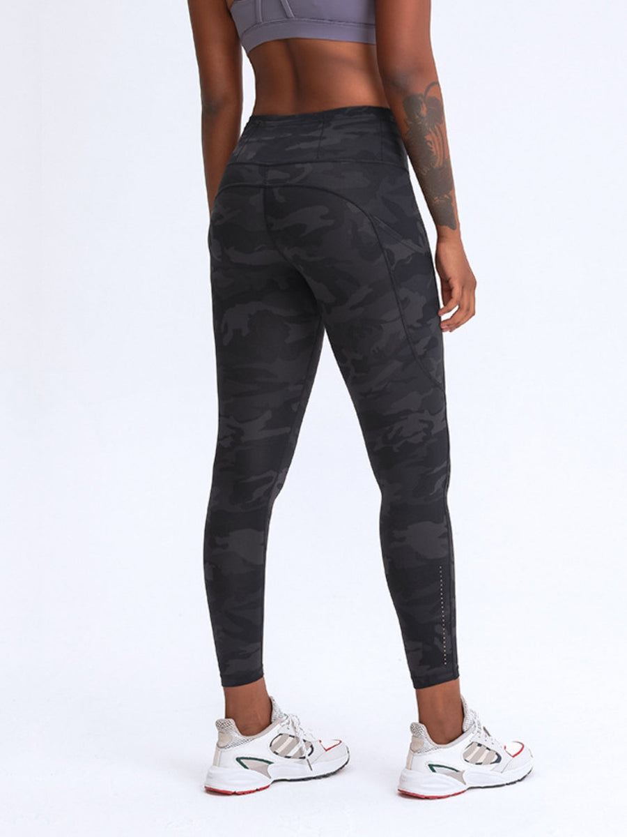 Black camouflage print performance leggings with pockets and reflective ankle detail.