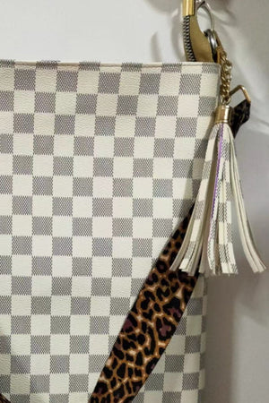 Cream checkered crossbody bag with leopard print strap and tassel detail.