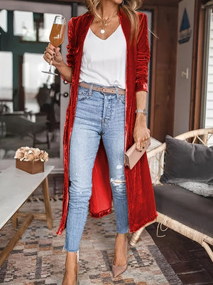 Red velvet duster coat with fluid silhouette, open front, long sleeves, worn with jeans and white top.