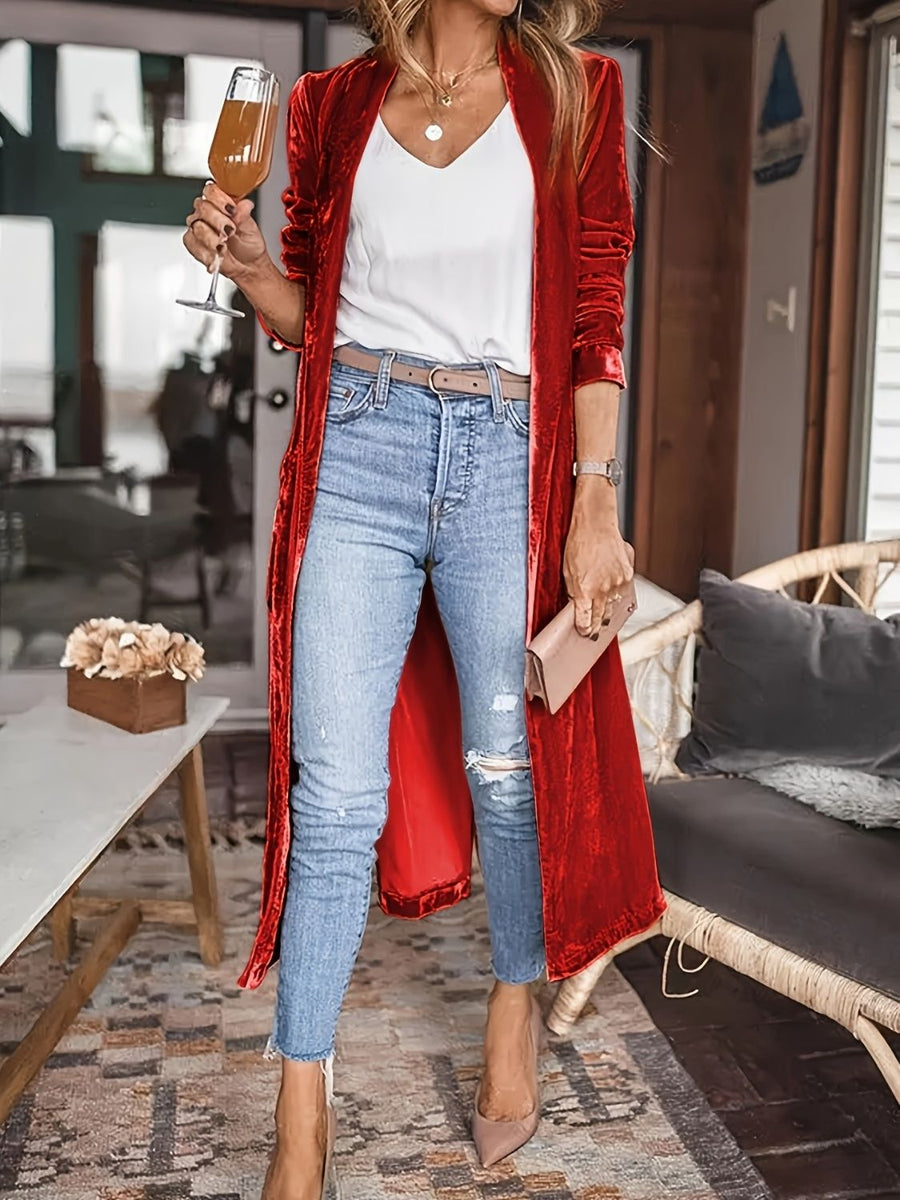 Red velvet duster coat with fluid silhouette, open front, long sleeves, worn with jeans and white top.