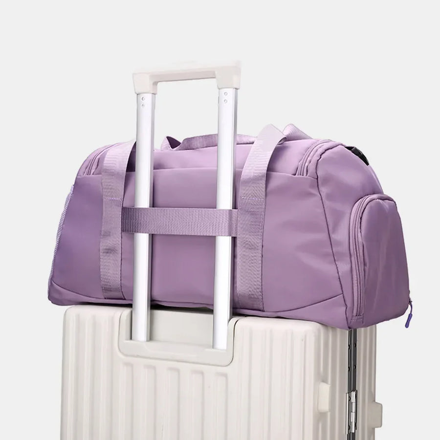 Sportsnew Nylon Duffle in Mauve with mesh pocket and adjustable strap, resting on a suitcase.