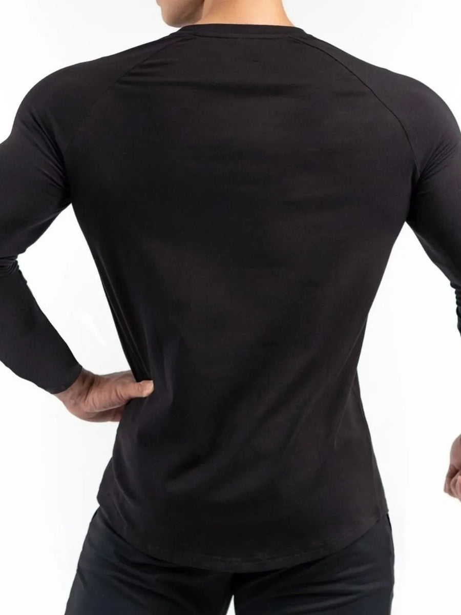 Black long sleeve performance top with raglan sleeves and a curved hem.