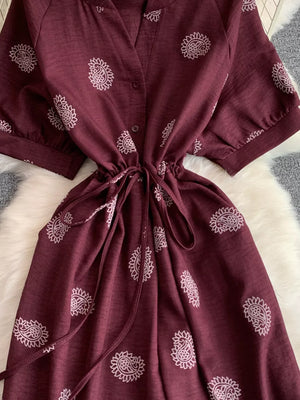 Burgundy paisley print drawstring jumpsuit with short sleeves and cinched waist.