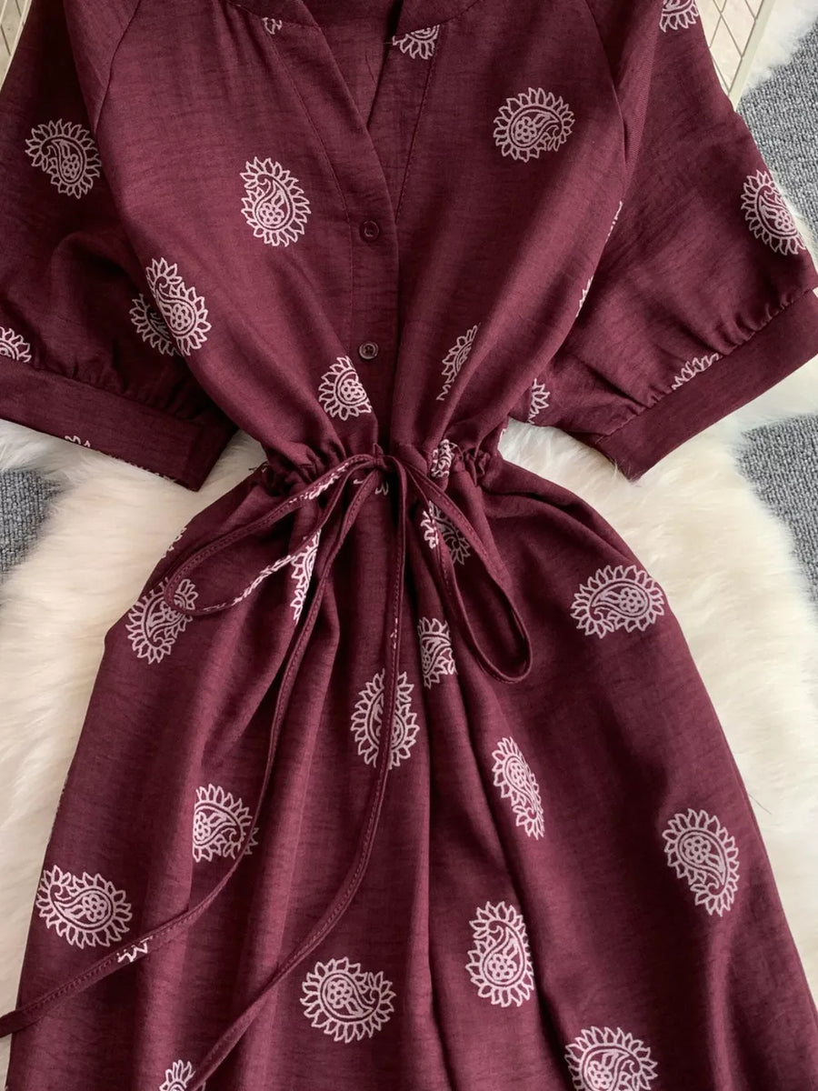 Burgundy paisley print drawstring jumpsuit with short sleeves and cinched waist.