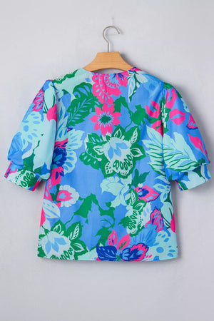 Vibrant floral v-neck blouse with relaxed fit and puff sleeves in blue, green, and pink.