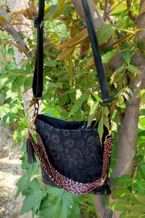 Black leopard print embossed crossbody bag with tassel and leopard print strap.