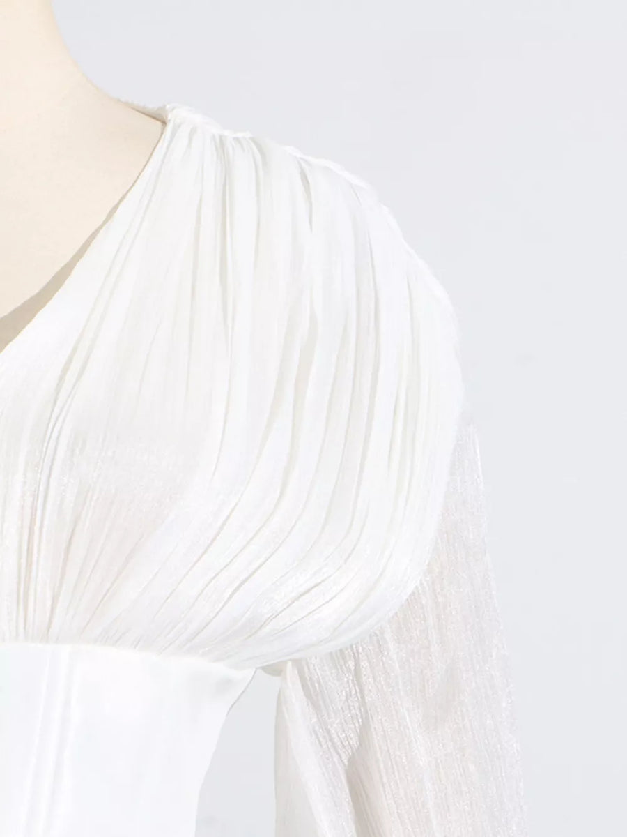 White mini dress with ruffled shoulder detail and sheer balloon sleeves.