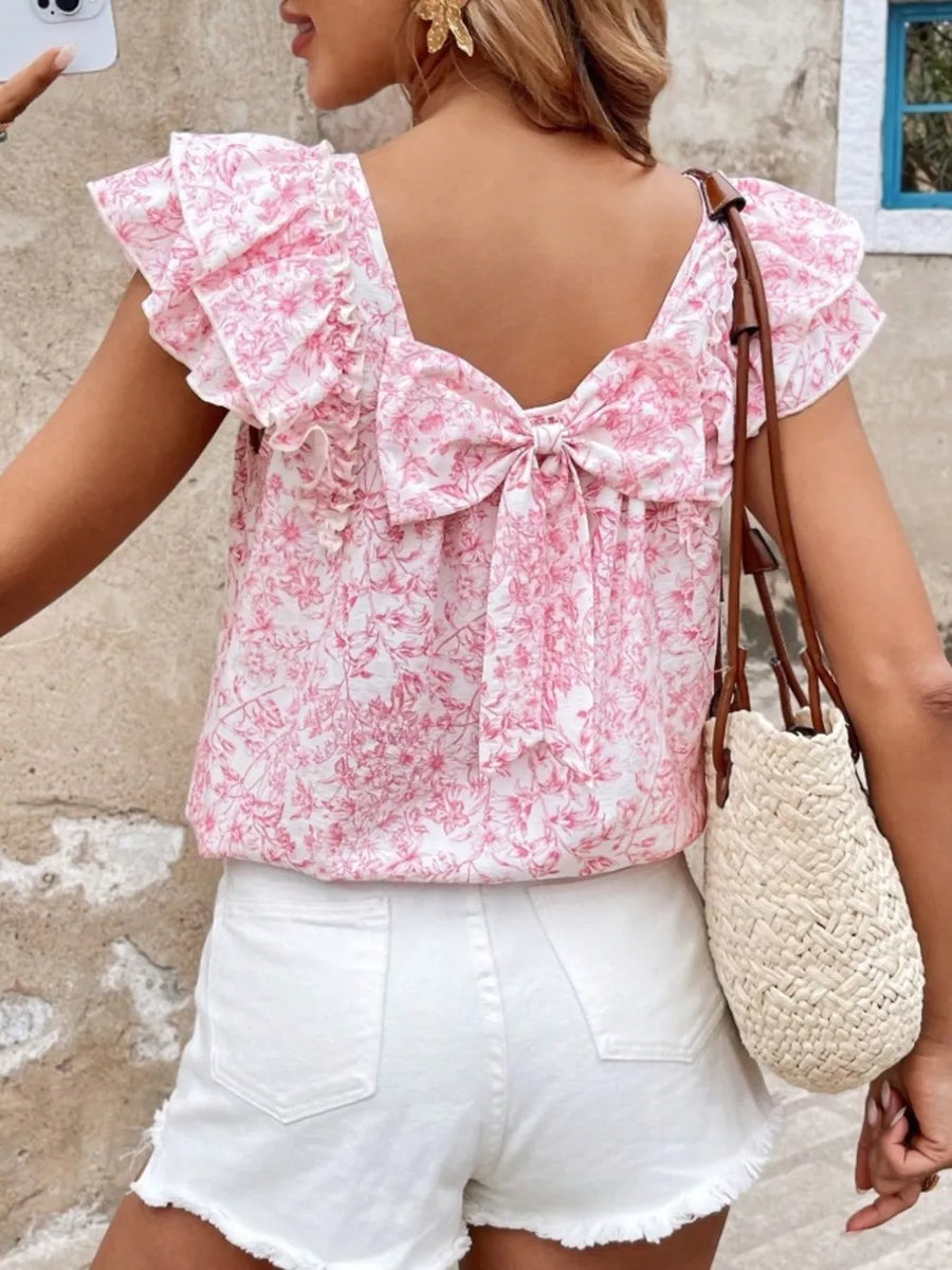 Pink floral ruffle blouse with back bow detail and flutter sleeves.