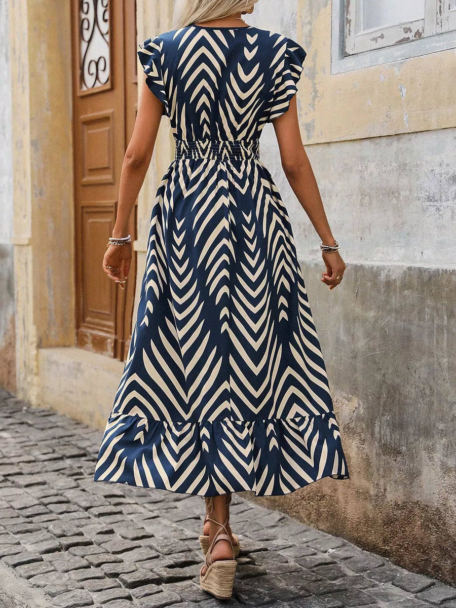 Dark blue and cream geometric print midi dress with ruffled hem and cap sleeves.