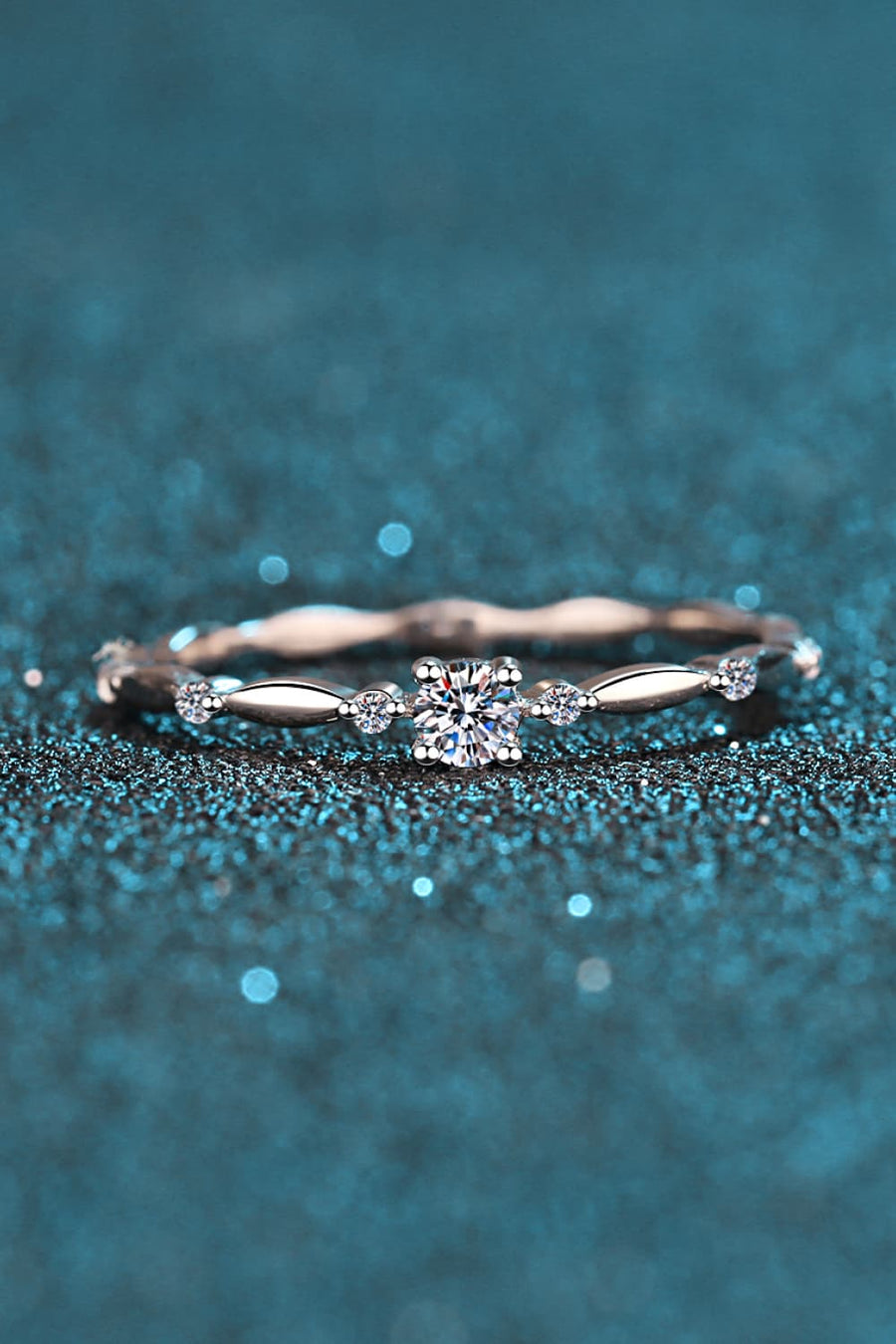 Delicate silver band ring with a central diamond and small accent stones, scalloped detail.