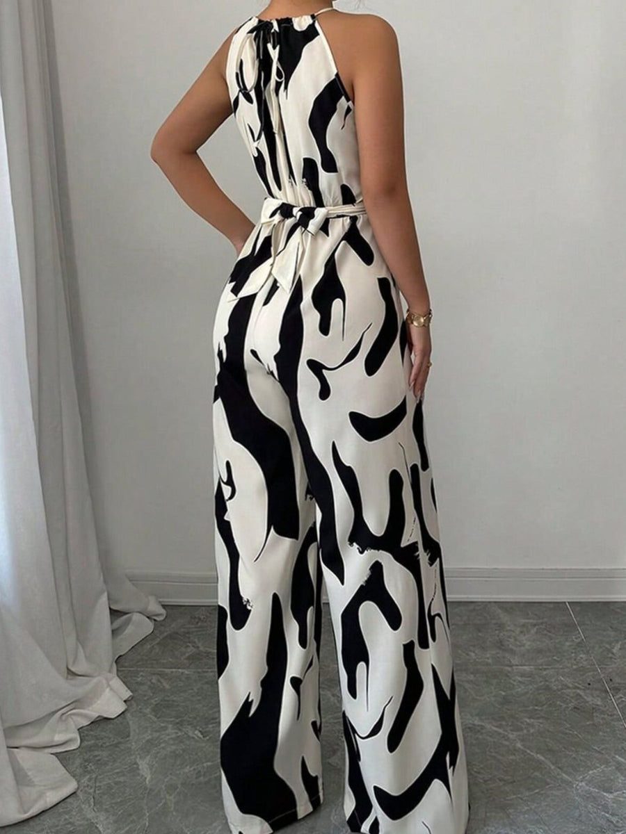 Chic abstract print halter jumpsuit with tie waist and wide legs.