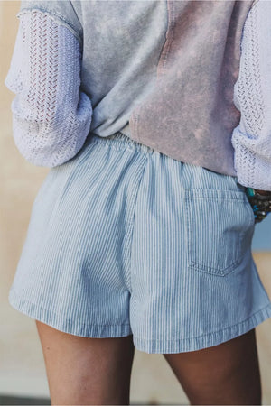 Light blue pinstripe denim shorts with a relaxed fit and drawstring waist, featuring a back pocket.