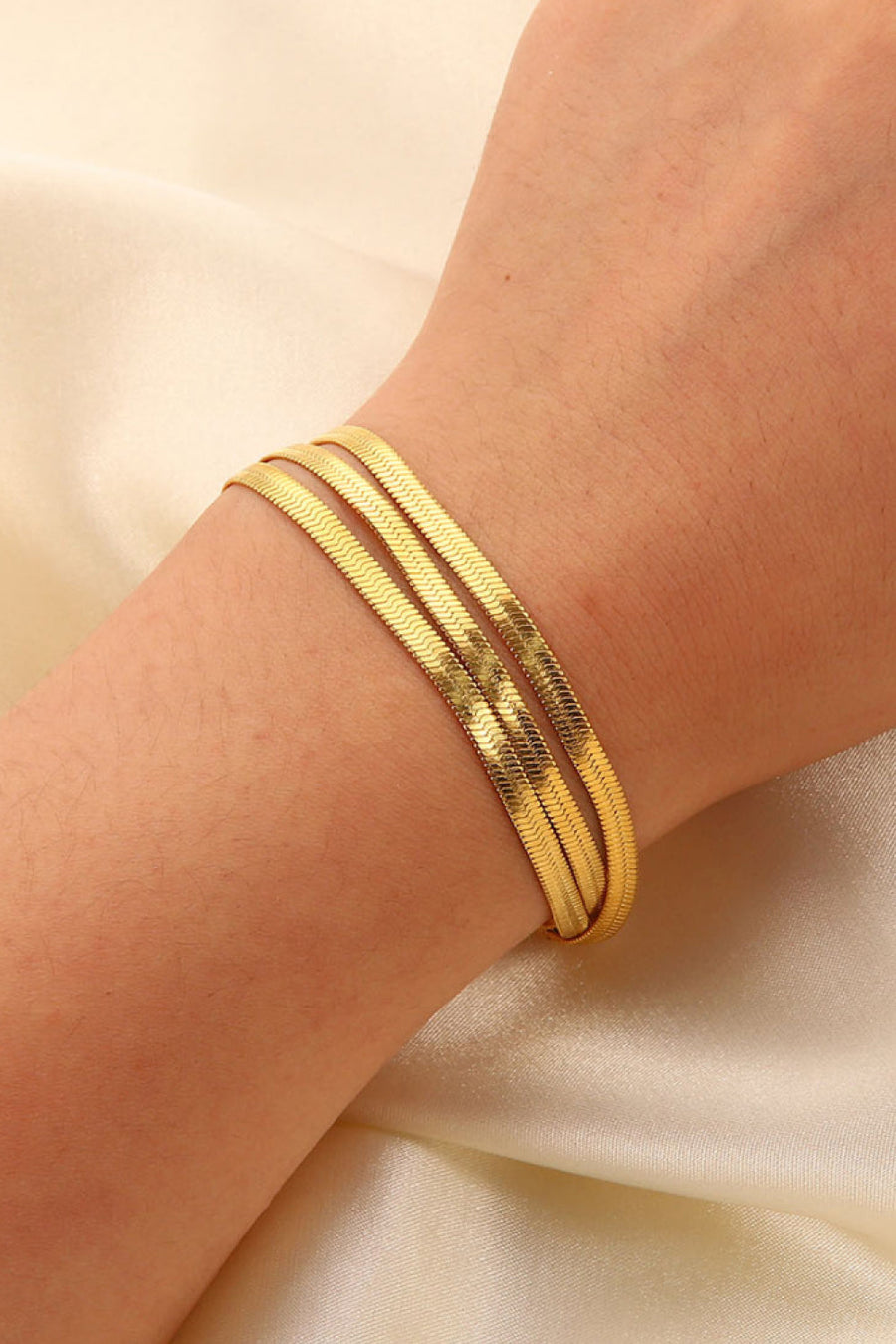 Triple gold herringbone chain bracelet crafted with a flat, flexible design.