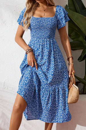 Blue floral smocked square neck midi dress with ruffled sleeves and tiered skirt.