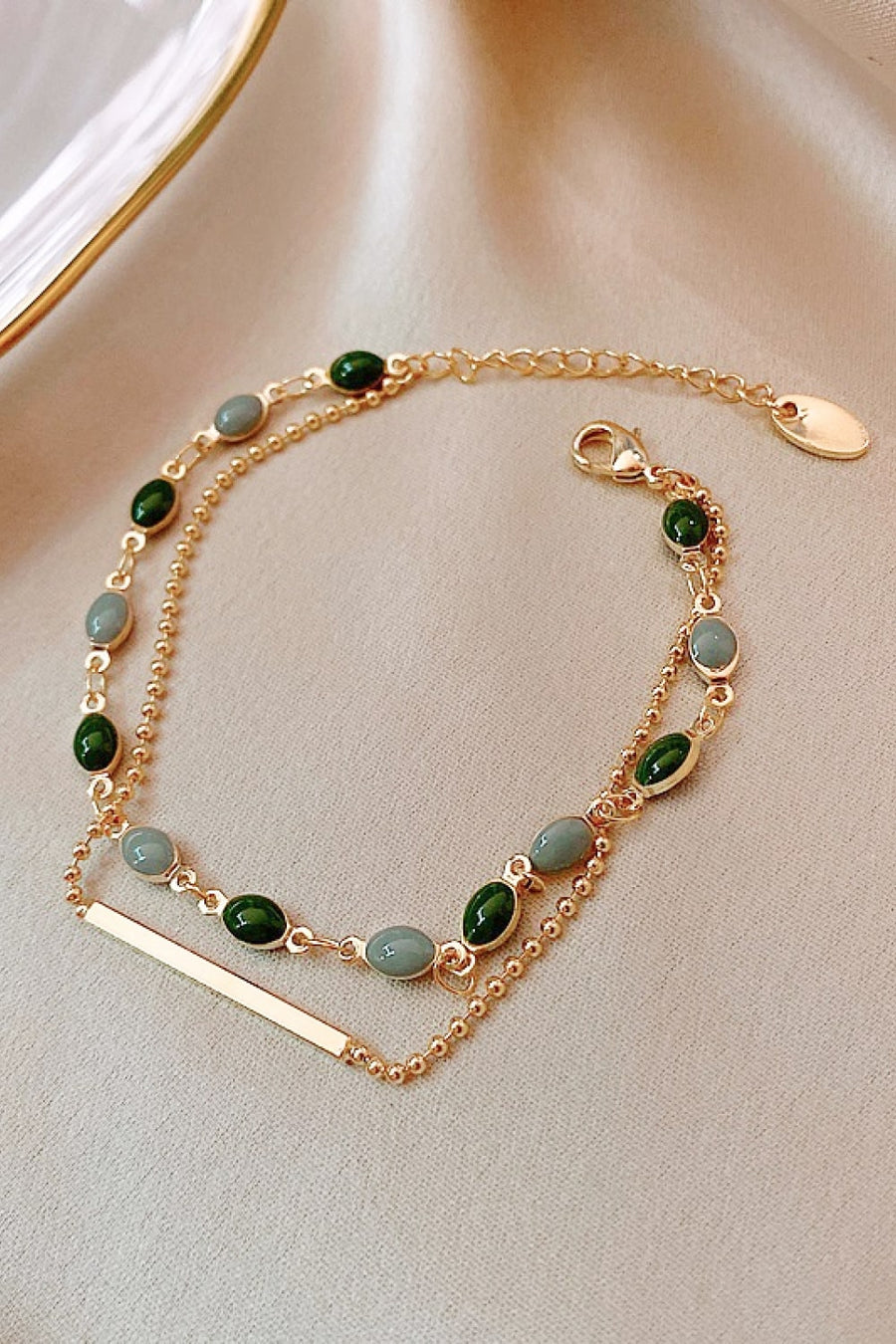 Dual chain bracelet in gold with green and grey stones and a bar accent