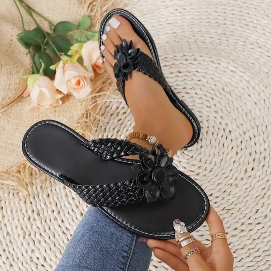 Black braided thong sandals with 3D floral accents and elegant details.