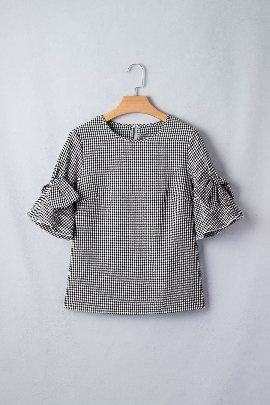 Black and white gingham polyester shirt with ruffled bow tie sleeves.