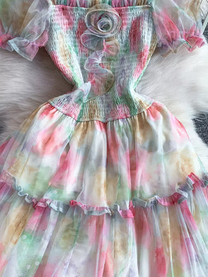 Floral tiered midi dress with smocked bodice and sheer sleeves in a pastel tie-dye print.