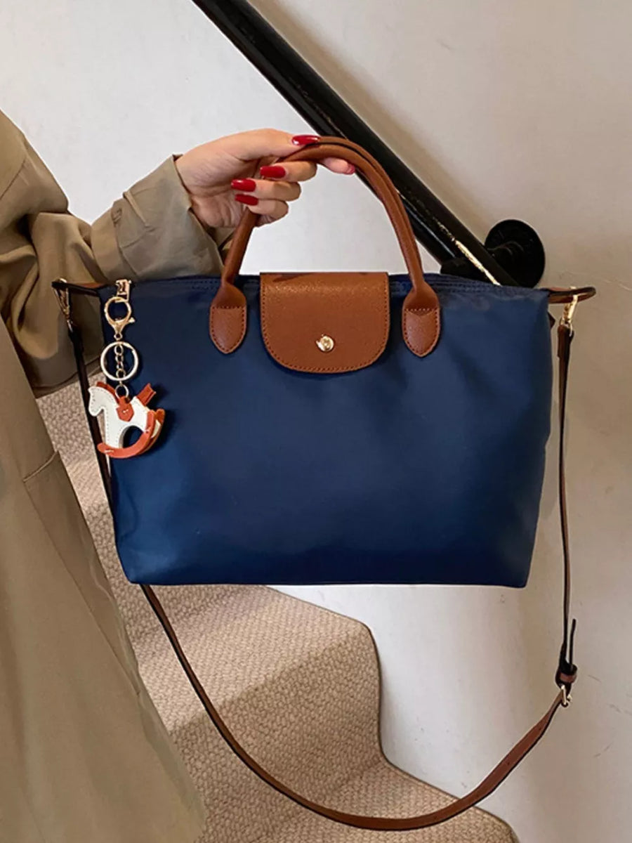 Navy nylon tote bag with brown leather accents and a horse charm.