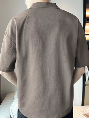 Taupe cotton polo shirt with textured fabric and short sleeves.