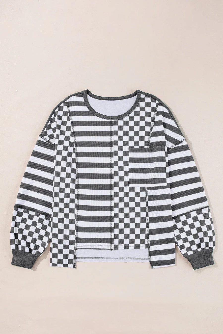 Asymmetrical knit top in black with patchwork stripes and checkerboard pattern.