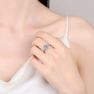 Emerald cut moissanite halo ring in sterling silver with blue accents.