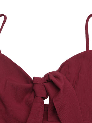 Burgundy bow-knot detail spaghetti strap romper with textured fabric.