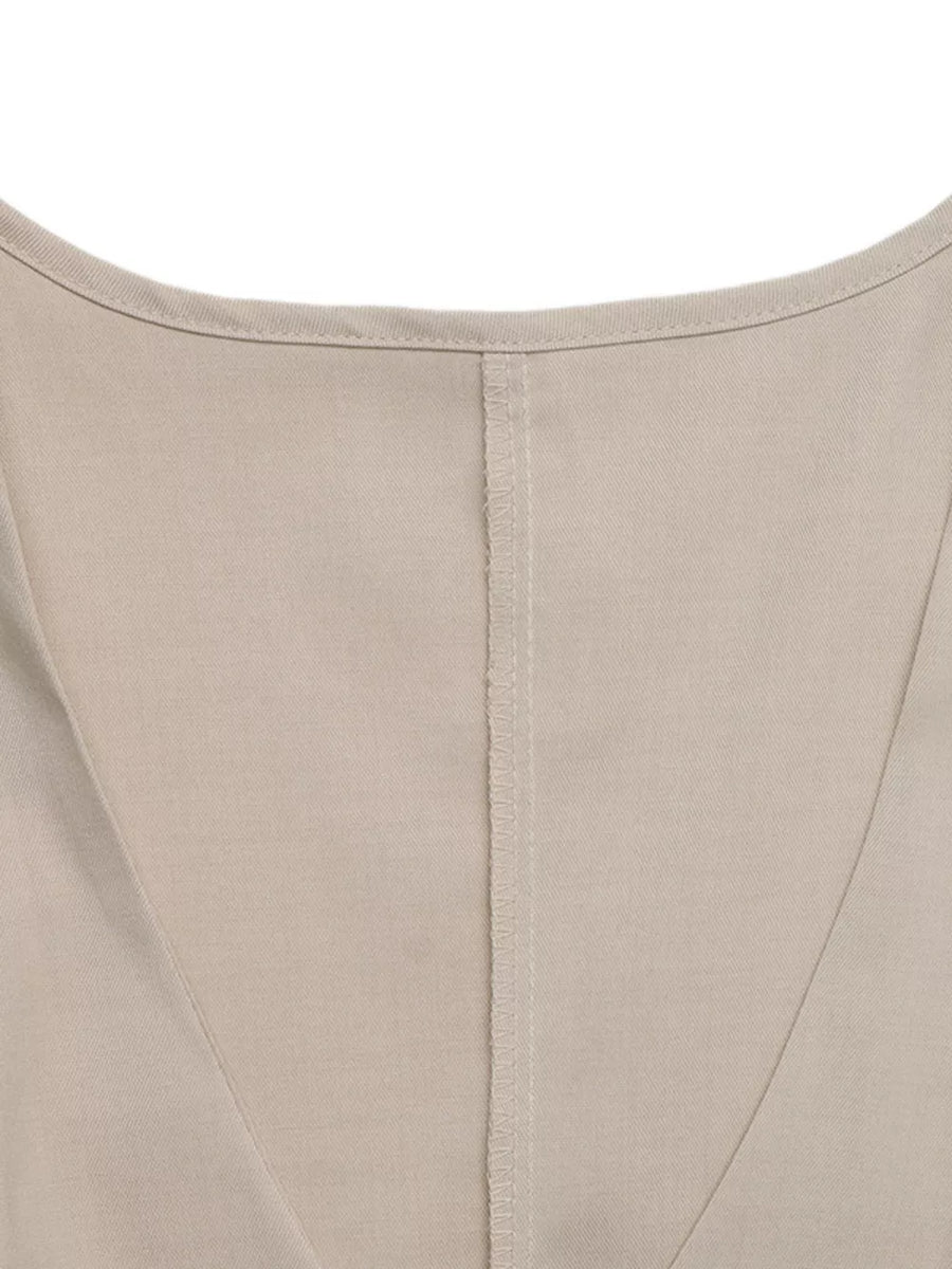 Beige sleeveless wrap top detail with V-neckline and center seam on polyester fabric.