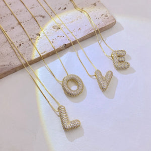 Puffed initial necklaces with cubic zirconia on delicate gold chains, spelling LOVE.