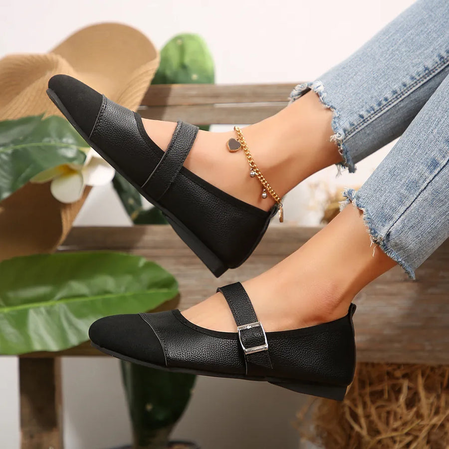 Black Mary Jane flats with buckle strap and cap toe detail.