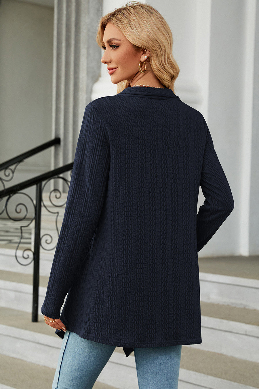 Dark blue textured knit cardigan with asymmetrical hem and long sleeves.