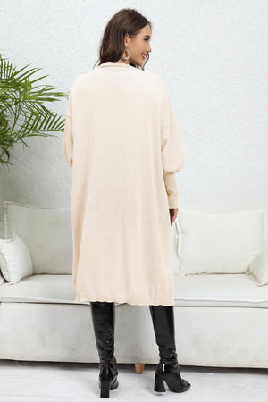 Beige long cardigan with balloon sleeves and ribbed cuffs, worn with black boots.