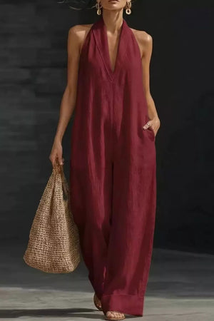Burgundy halter-neck jumpsuit with pockets, deep V-neck, and wide legs.