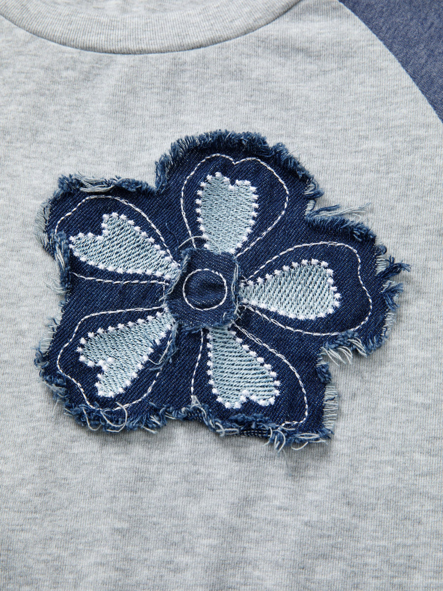 Raglan shirt with a distressed denim embroidered flower patch detail.