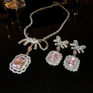Silver bow crystal drop earrings and necklace with pink gemstones.