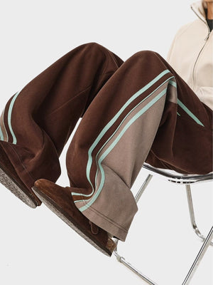 Brown joggers with side stripes and drawstring waist, styled with casual shoes.