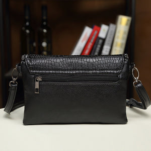 Black crossbody bag featuring chain strap detail and crocodile-print
