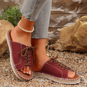 Red canvas open-toe flats with lace-up detail and espadrille sole.