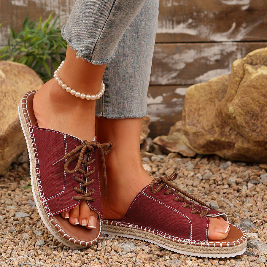 Red canvas open-toe flats with lace-up detail and espadrille sole.