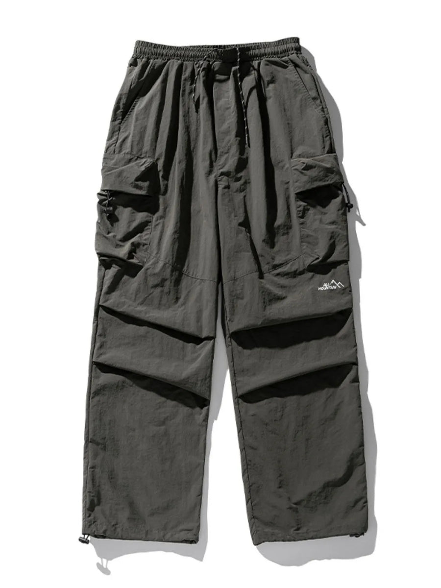 Oversized dark gray utility cargo pants with multiple pockets and drawstring waist.