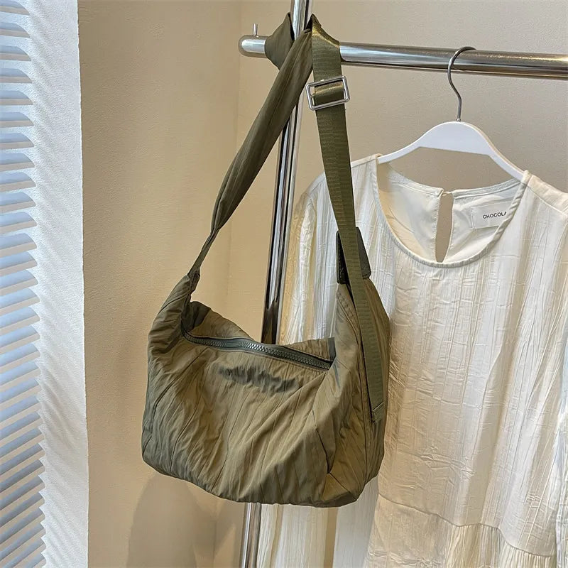 Quilted crescent shoulder bag in olive with a zippered front and adjustable strap.