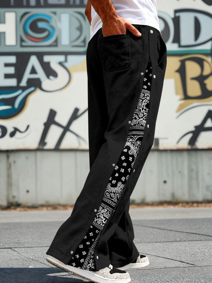 Black sweatpants with wide legs and side snaps, featuring a bandana print stripe.