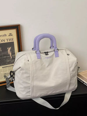 Sleek grey nylon travel bag with purple handles and adjustable shoulder strap.