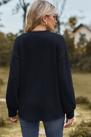 Dark blue cable knit v-neck pullover sweater with textured fabric and long sleeves.